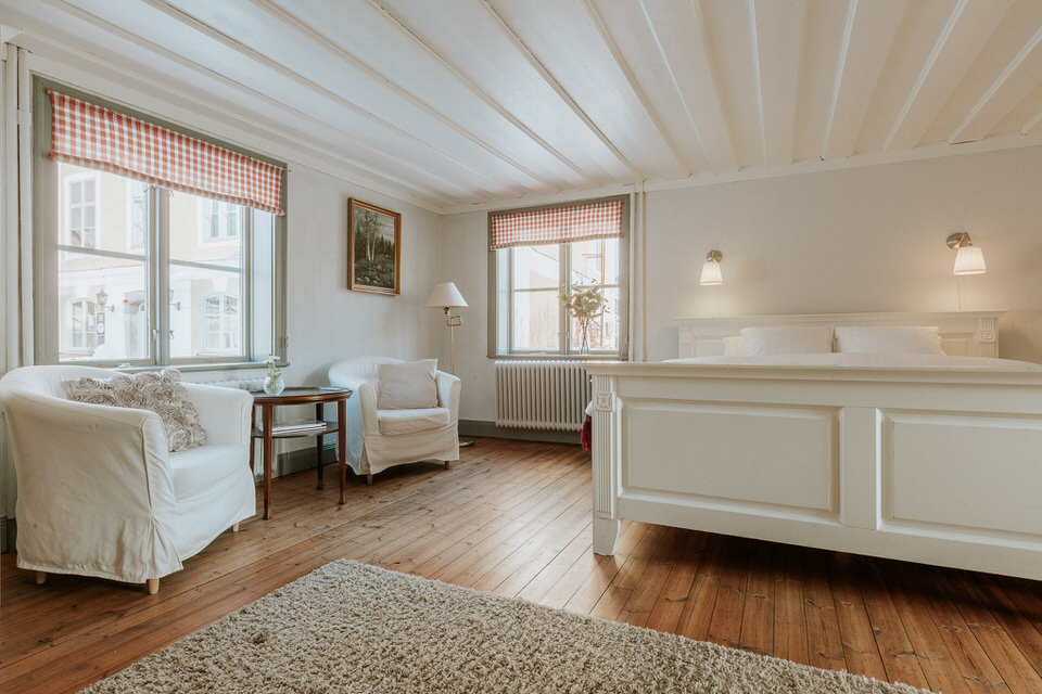 Ljust gästrum med dubbelsäng och fåtöljer