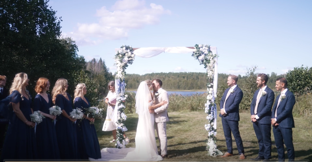 Brudpar vigs under en blomsterbåge på udden vid vattnet, Schenströmska Herrgården