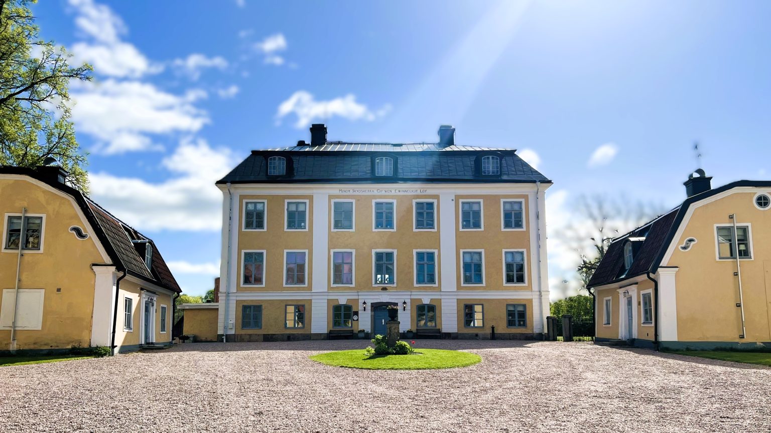 Schenstr&ouml;mska Herrg&aring;rden med flyglarna och g&aring;rdsplanen en solig dag