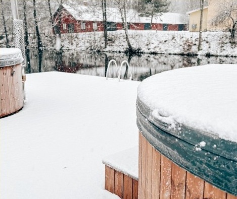 Vedeldade badtunnor vid ån i vinterlandskap