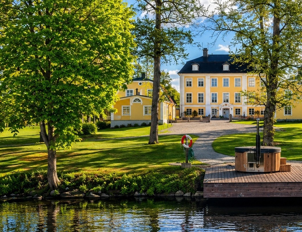 Herrgården i vårgrönska med badtunna vid bryggan